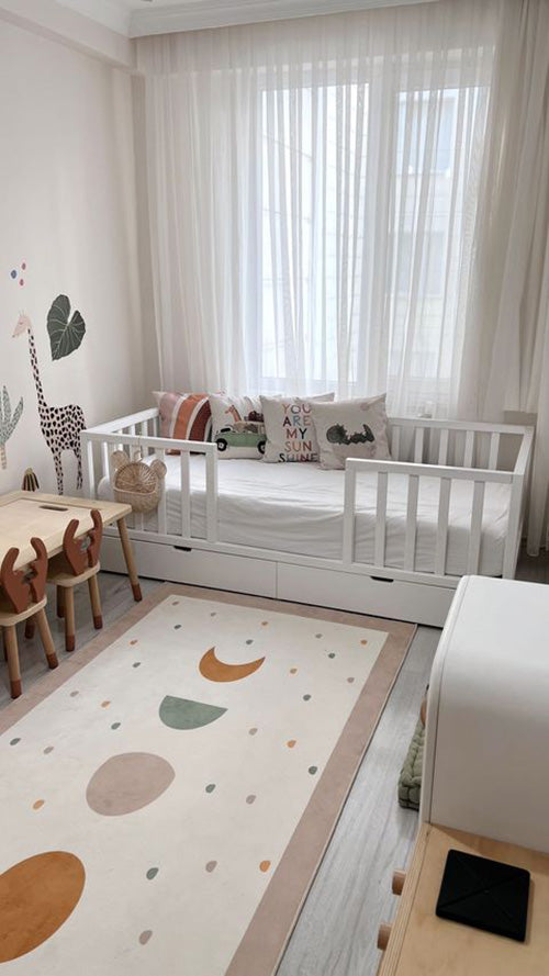 Çocuk odasındaki Bohem halı, yastıklarla beraber. Halının rengarenk daireler ve ay şekilli desenleri dikkat çekiyor.