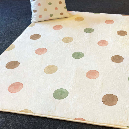 Yumuşak dokulu, desenli çocuk halısı. Halının üzerine yerleştirilmiş bir yastık, aynı nokta desenine sahip. Renkli noktaların keyifli görünümü odanın atmosferini canlandırıyor.