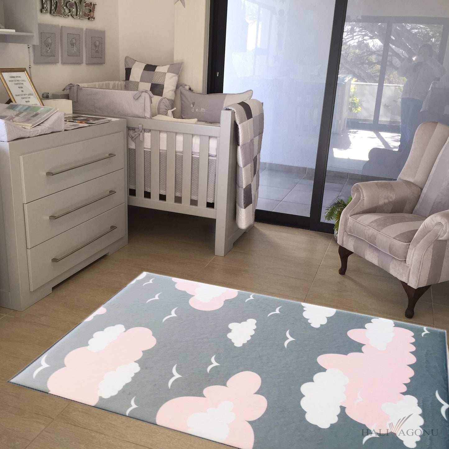 Halı Vagonu HV326P bulutlu pembe çocuk odası halısı, modern bir çocuk odasında yer almakta. Gri renkli halının üstünde pembe bulutlar ve yan tarafında bir bebek beşiği yer alıyor.