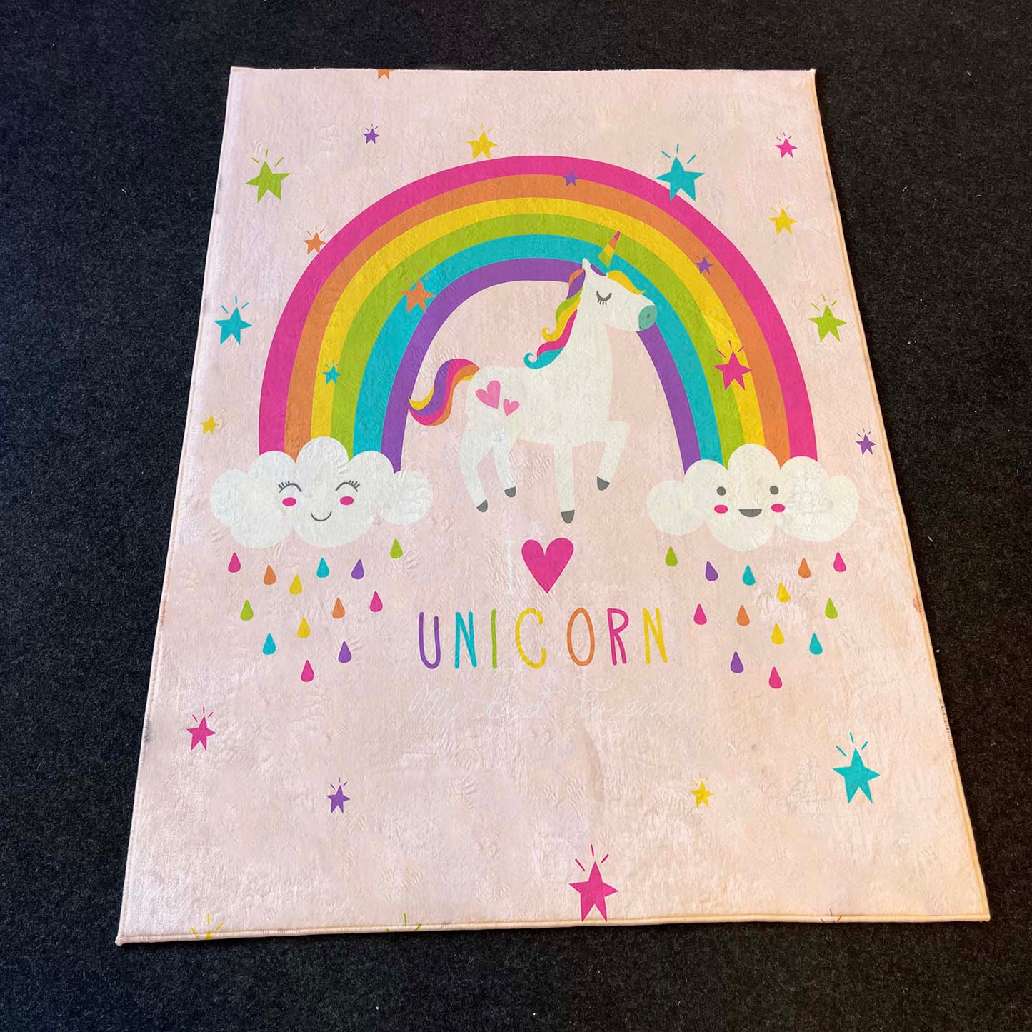 Pembe zemin üzerinde unicorn figürü ve renkli yağmur damlaları yer alan halı, modern bir çocuk odasında estetik bir görüntü sunuyor.