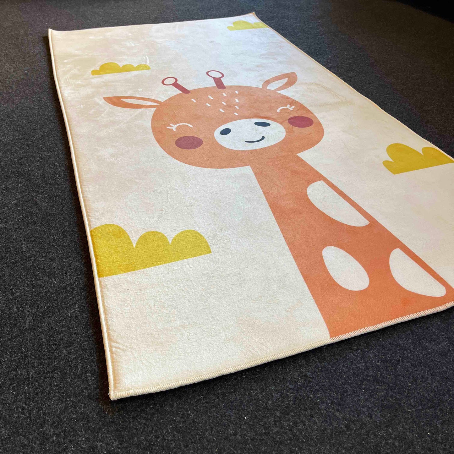 Zürafa deseninin ön planda olduğu halı, dikkat çekici renklerle tasarlanmış.