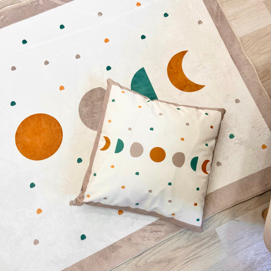 Bohem tarzı çocuk halısı ve üzerine yerleştirilmiş yastık. Halının üzerindeki desenler renkli daireler ve ay şekillerinden oluşuyor.