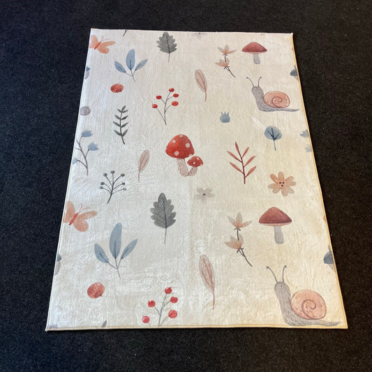 Düz bir zemin üzerinde yan yatan kahverengi ve kırmızı mantarlarla bezeli çocuk halısının yakın plan görüntüsü.