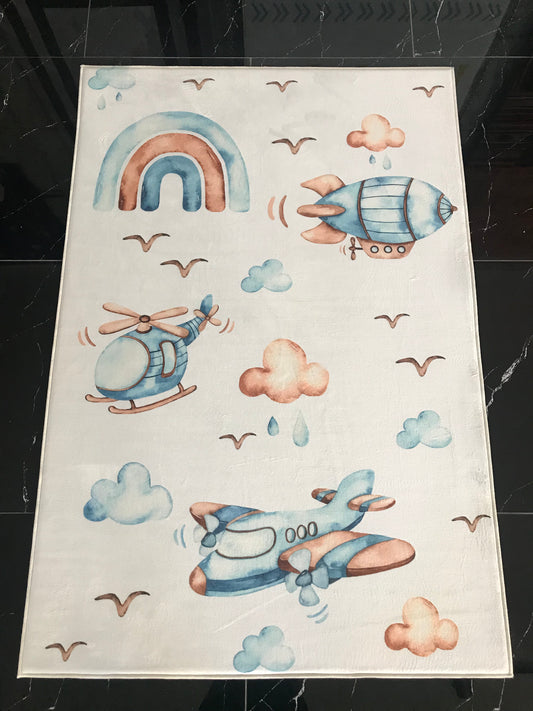 Mavi ve pembe tonlarında helikopter ve uçak desenleri olan halının üstten görünümü.