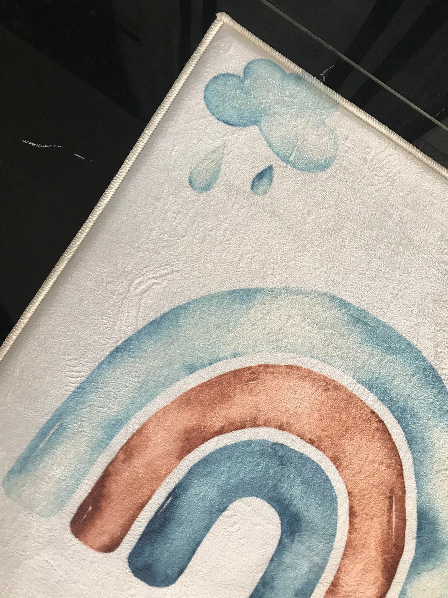 Yağmur damlalarının olduğu renkli bir gökkuşağı deseni detayına sahip halı.
