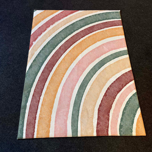 Dikey yerleştirilmiş, Gökkuşağı desenli yuvarlak çocuk halısının detayları.