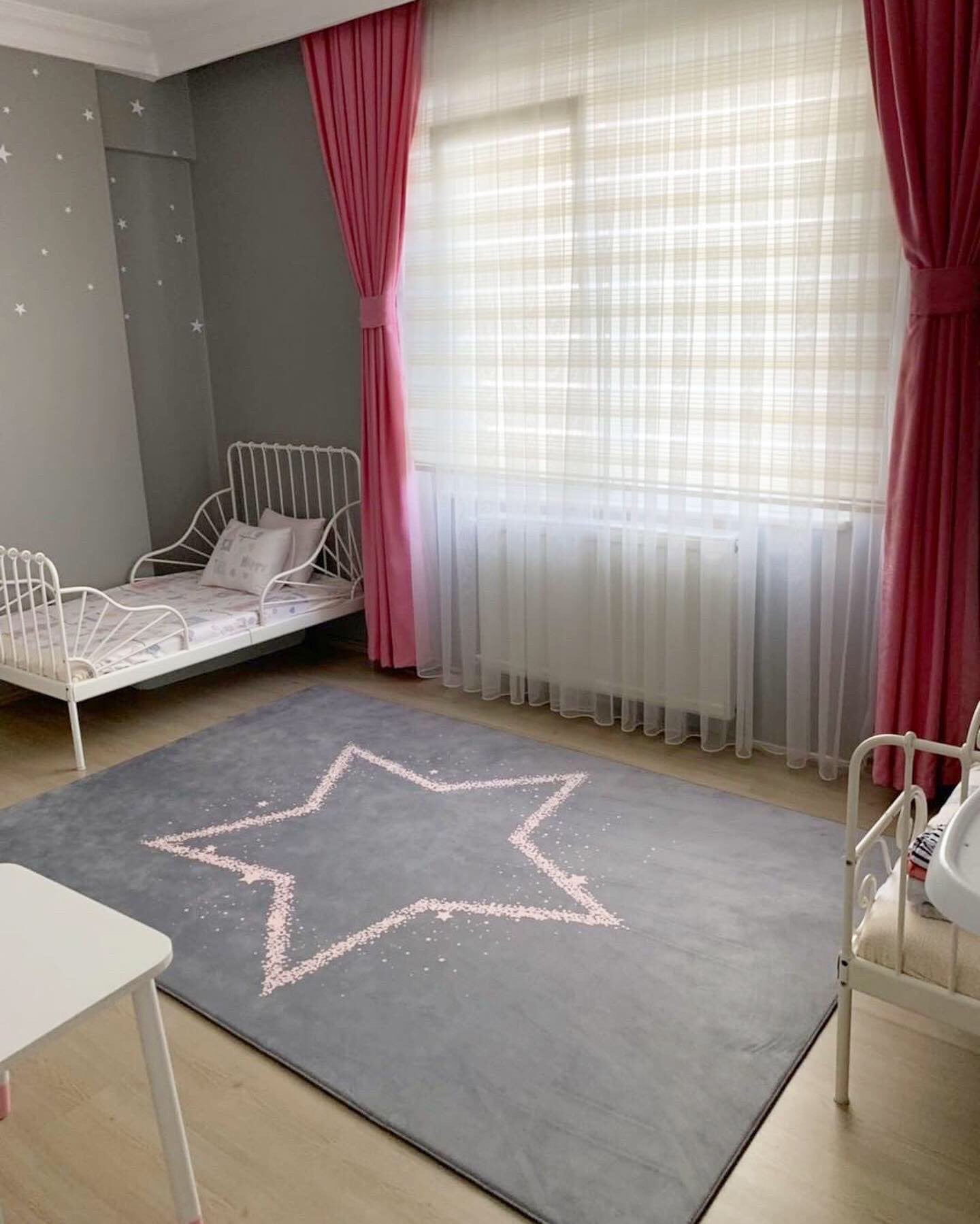Gri ve pembe renklerde yıldızlı çocuk odası halısı, pembe perdeler ile aydınlık bir odada serili. Yumuşak dokusu ile çocukların oyun alanına şıklık katıyor.