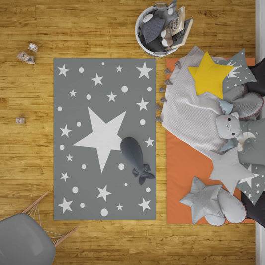 Çocuk odası için gri yıldızlı puantiyeli halı, oyuncaklar ve renkli yastıklarla dekore edilmiş alan.