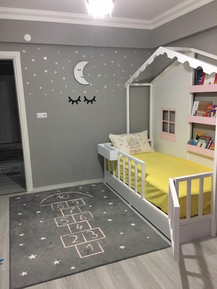 Çocuk odasında yer alan grafiti stilinde hopscotch deseni olan gri halı. Odanın duvarında yıldızlar ve ay figürü bulunuyor. Oda, modern çocuk yataklarıyla dekore edilmiş.