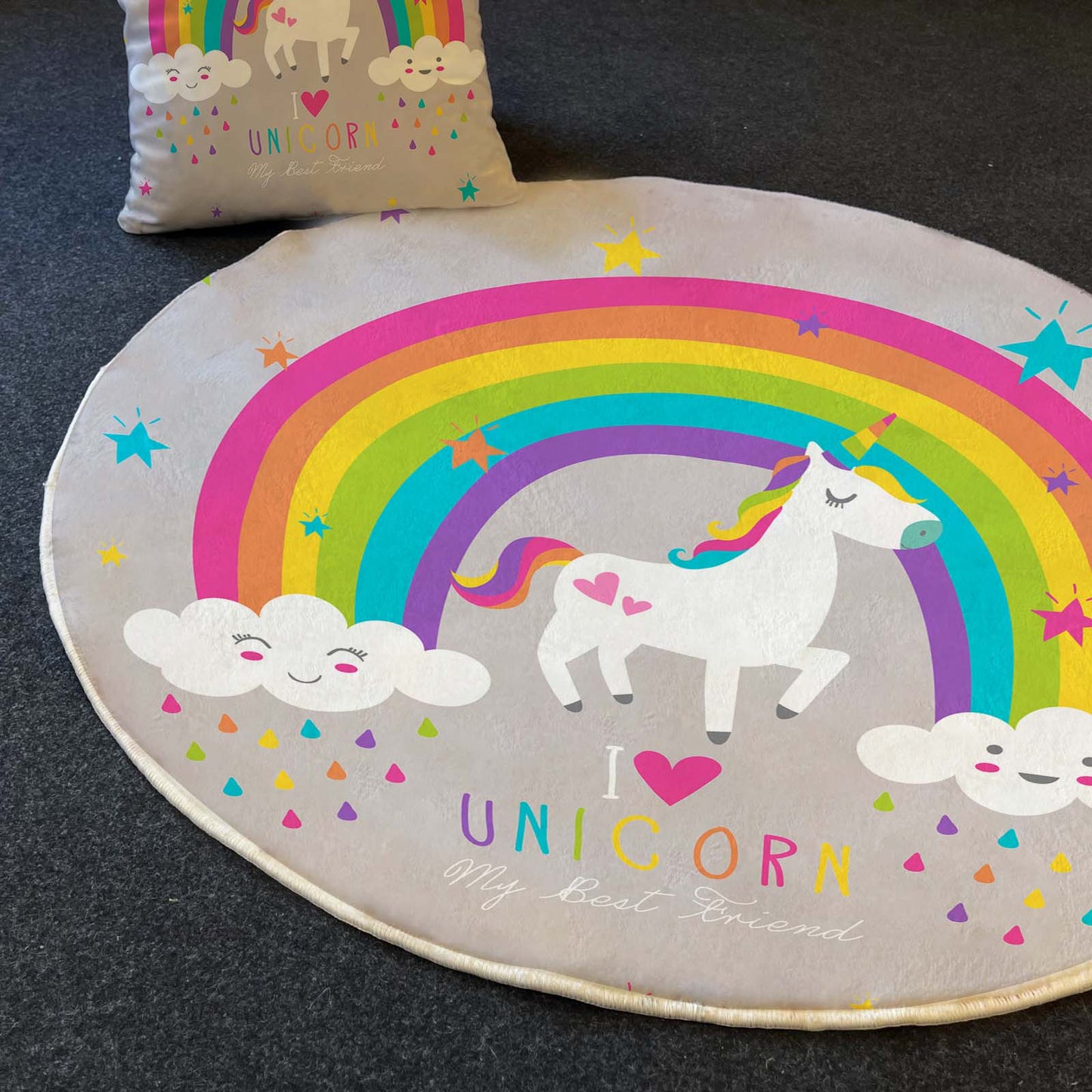 Dikdörtgen unicorn halısı ve yanındaki yastık, renkli gökkuşağı ve bulutlar ile süslenmiş.