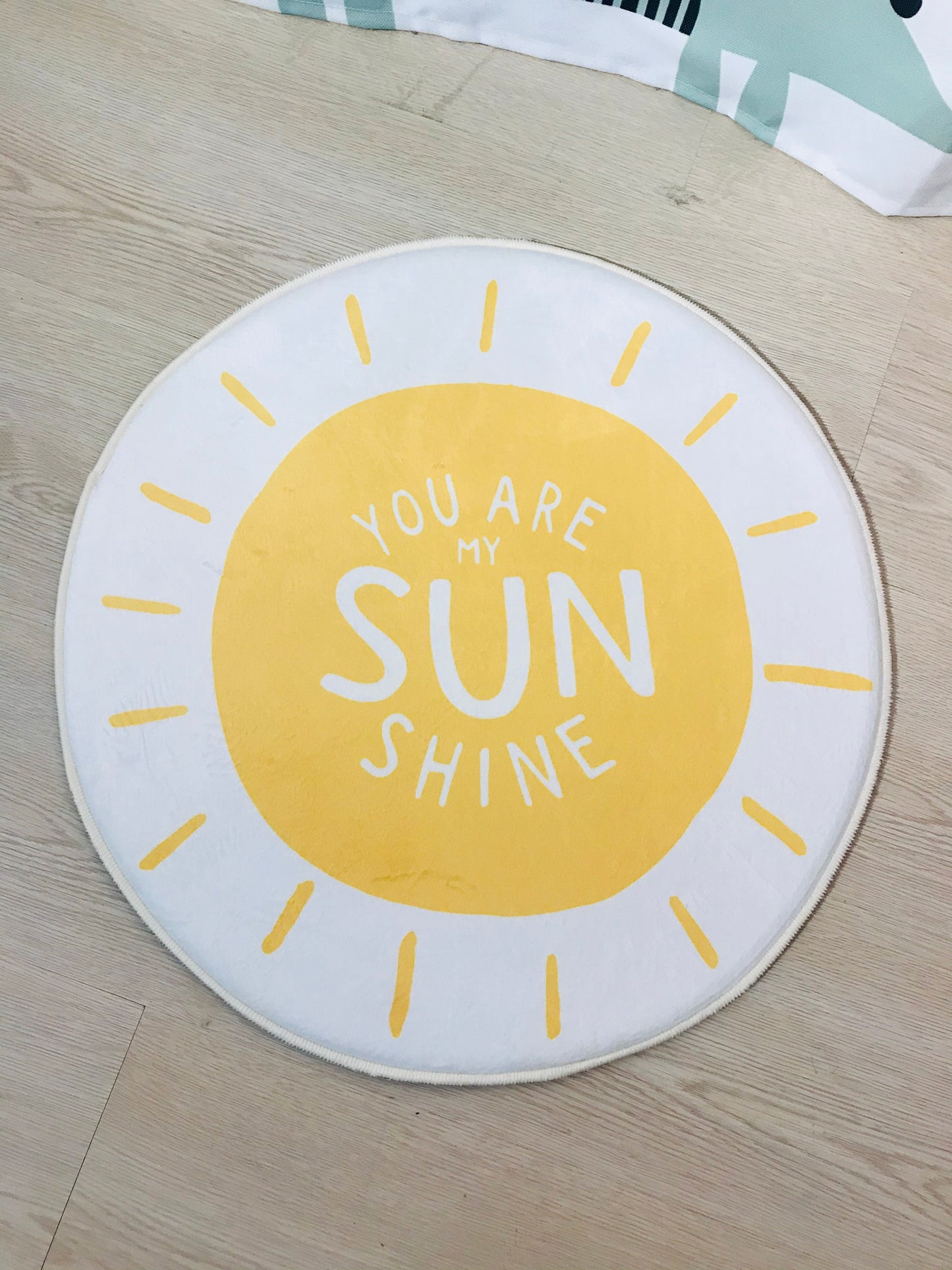 Beyaz zeminli yuvarlak halı, 'You Are My Sunshine' yazısı ile çocuk odalarında eğlenceli bir tema oluşturuyor.