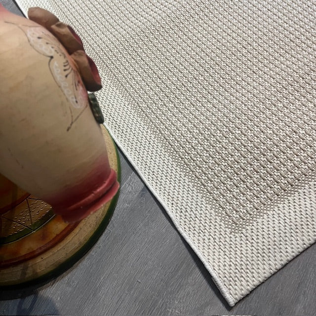 Krem rengi jüt sisal halının dikiş detaylarıyla birlikte üstten görünüm.