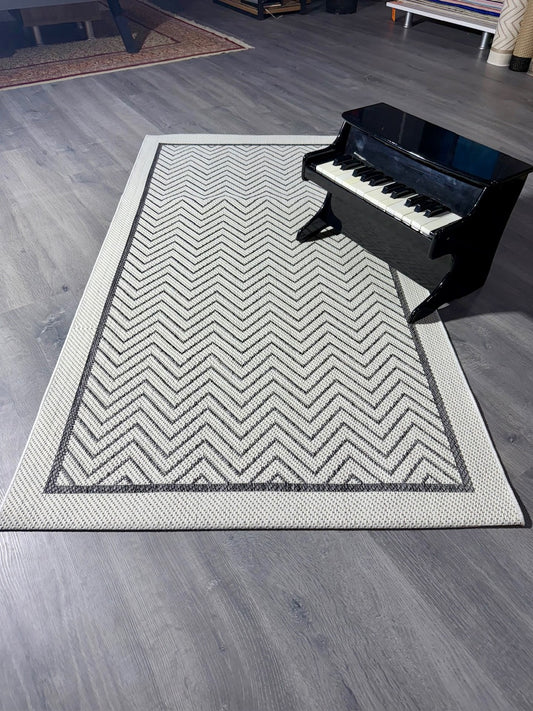 Antrasit beyaz zigzag desenli Halı Vagonu. Kenarında bir piyano ile birlikte geniş bir açıdan görünümü.