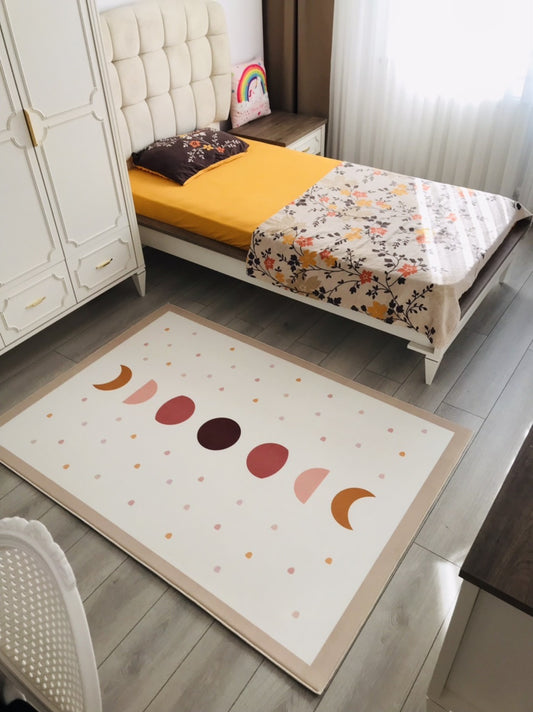 Modern tasarıma sahip, pastel tonlarda ay ve daire desenleriyle süslenmiş halı, çocuk odasında kullanıma uygun.