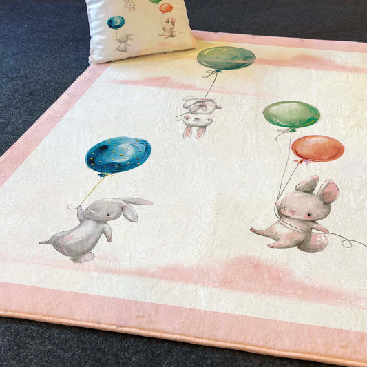 Pembe desenli çocuk odası halısı, havada balonlarla süzülen tavşanlar.