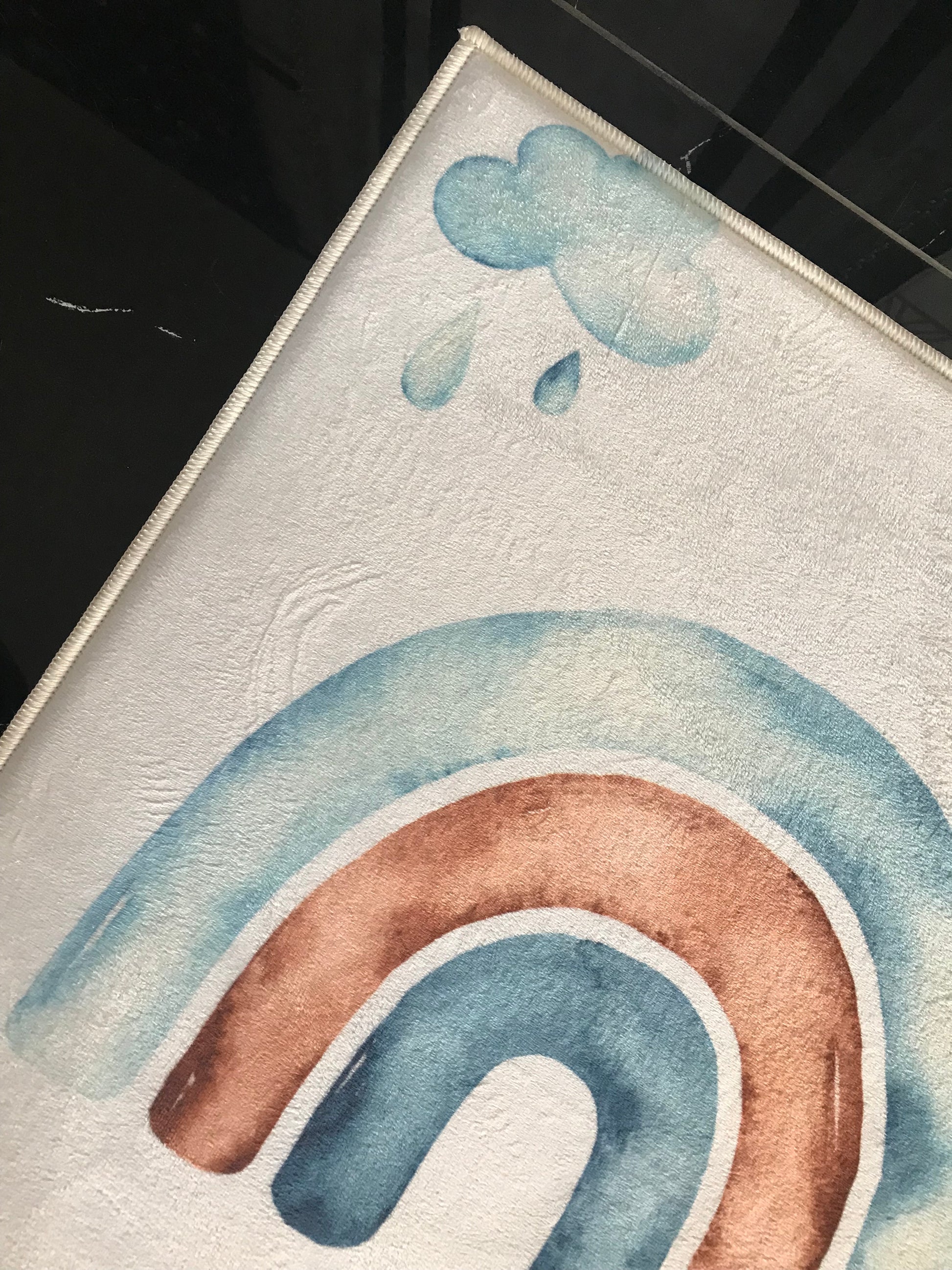 Yağmur damlalarının olduğu renkli bir gökkuşağı deseni detayına sahip halı.