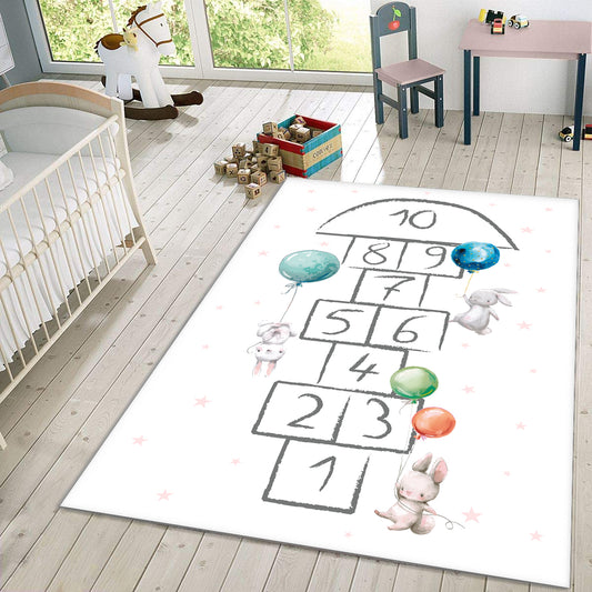 Renkli balonlarla süslenmiş, çocuklara özel bir zemin halısı. Üzerinde hopscotch (sek sek) oyunu alanı çizilmiş olup, sevimli tavşan figürleriyle dolu. Halı, çocuk odası dekorasyonu için ideal.