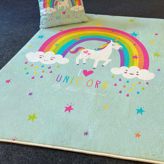 Gökkuşağı ve unicorn tasarımına sahip çocuk odası halısı, yanına yerleştirilmiş yastık ile birlikte, koyu bir zemin üzerinde serili.