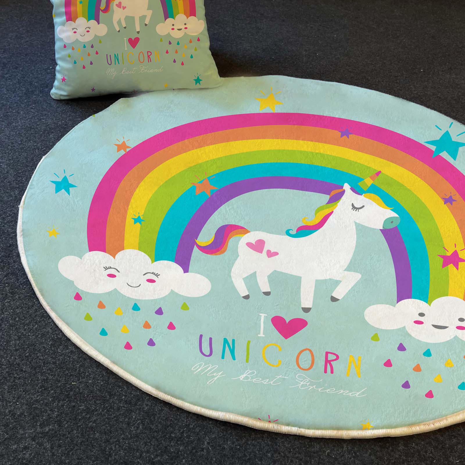 Dairesel bir tasarıma sahip unicorn desenli çocuk odası halısı, yanında aynı temalı yastık ile birlikte serilmiş.