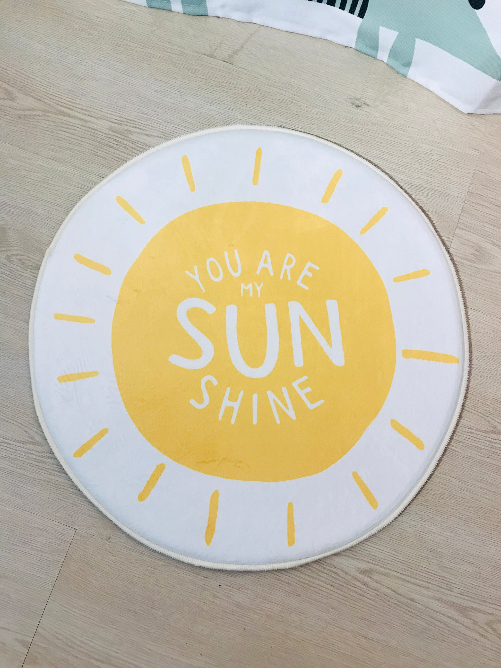 Beyaz zeminli yuvarlak halı, 'You Are My Sunshine' yazısı ile çocuk odalarında eğlenceli bir tema oluşturuyor.