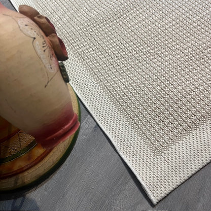 Krem rengi jüt sisal halının dikiş detaylarıyla birlikte üstten görünüm.